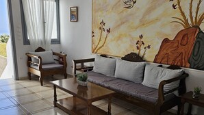 A living room with a sofa, two armchairs, a coffee table, and a painting on the wall. - Unique Leta (Santorini)