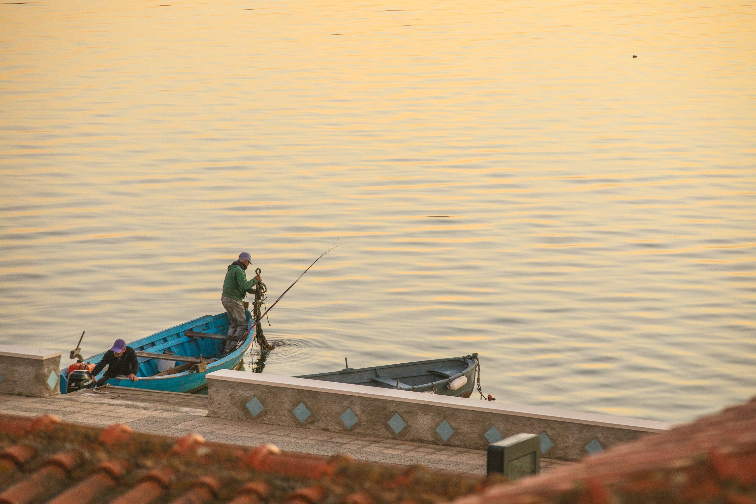Un río tranquilo con dos barcos, uno donde una persona está pescando.