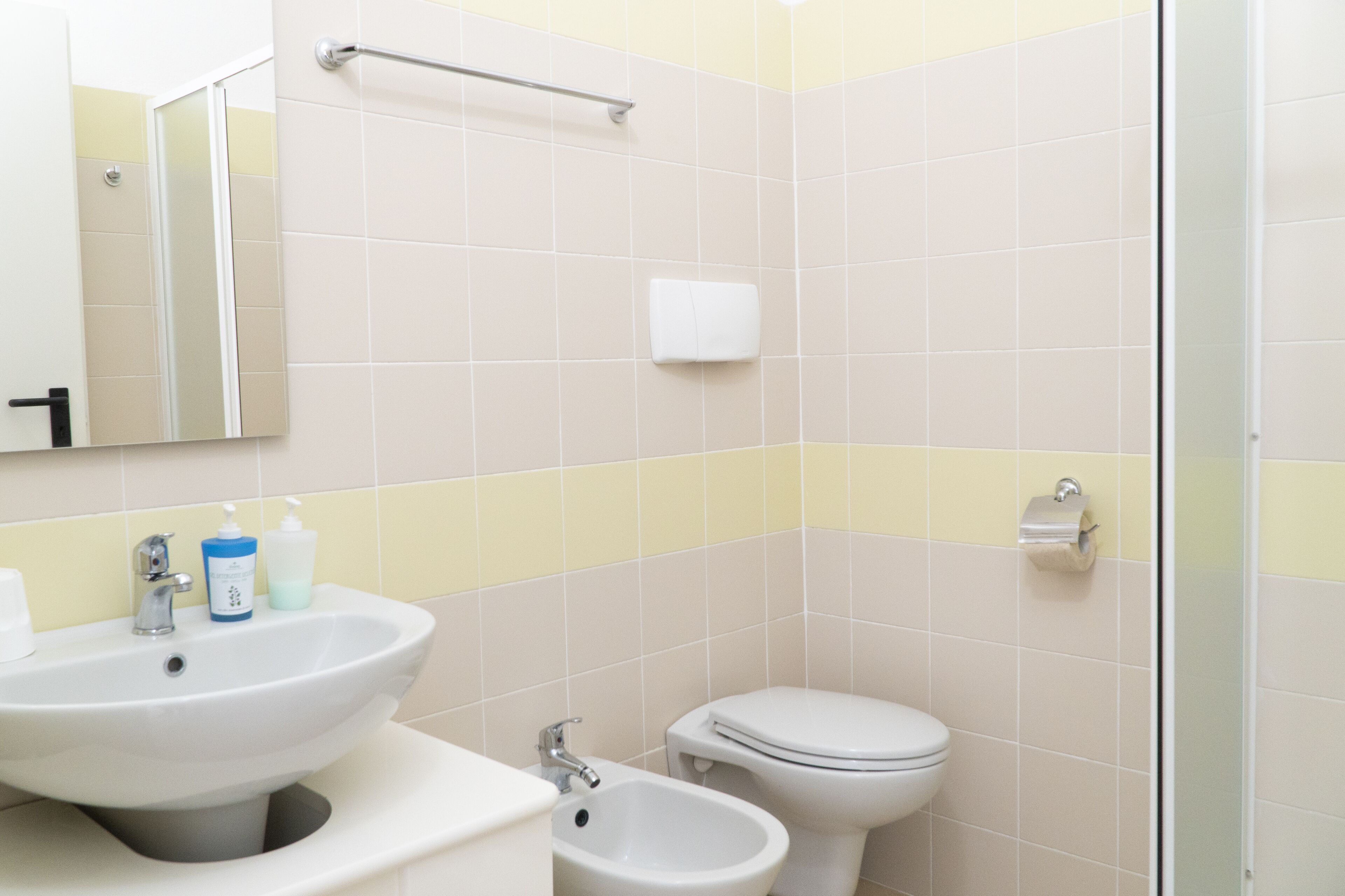 A bathroom with a sink, bidet, toilet, and a mirror.