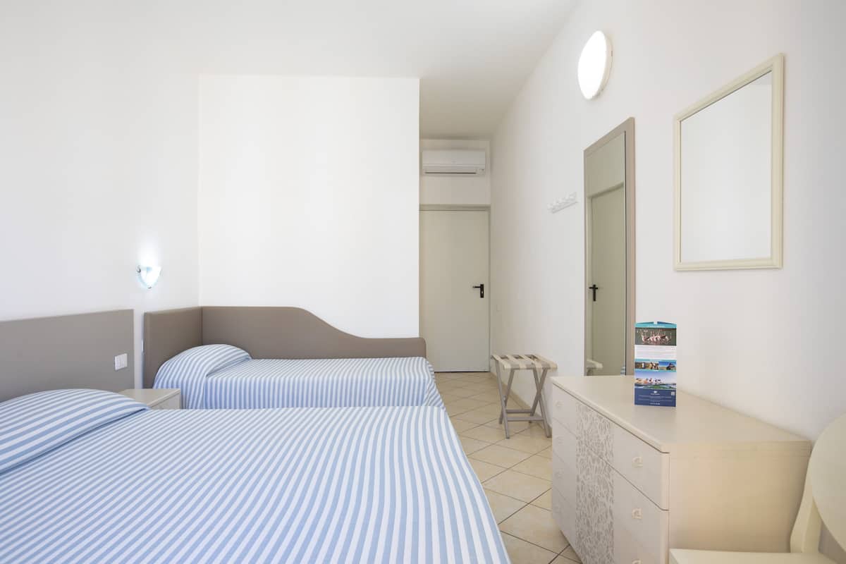 A hotel room with two beds, a dresser, a mirror, and a door leading to a bathroom.