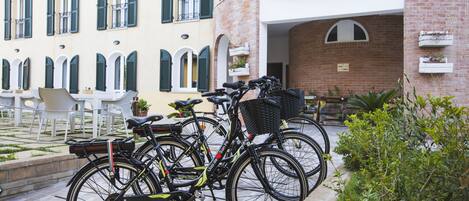 A courtyard with bicycles parked near a building with arched windows and outdoor seating.