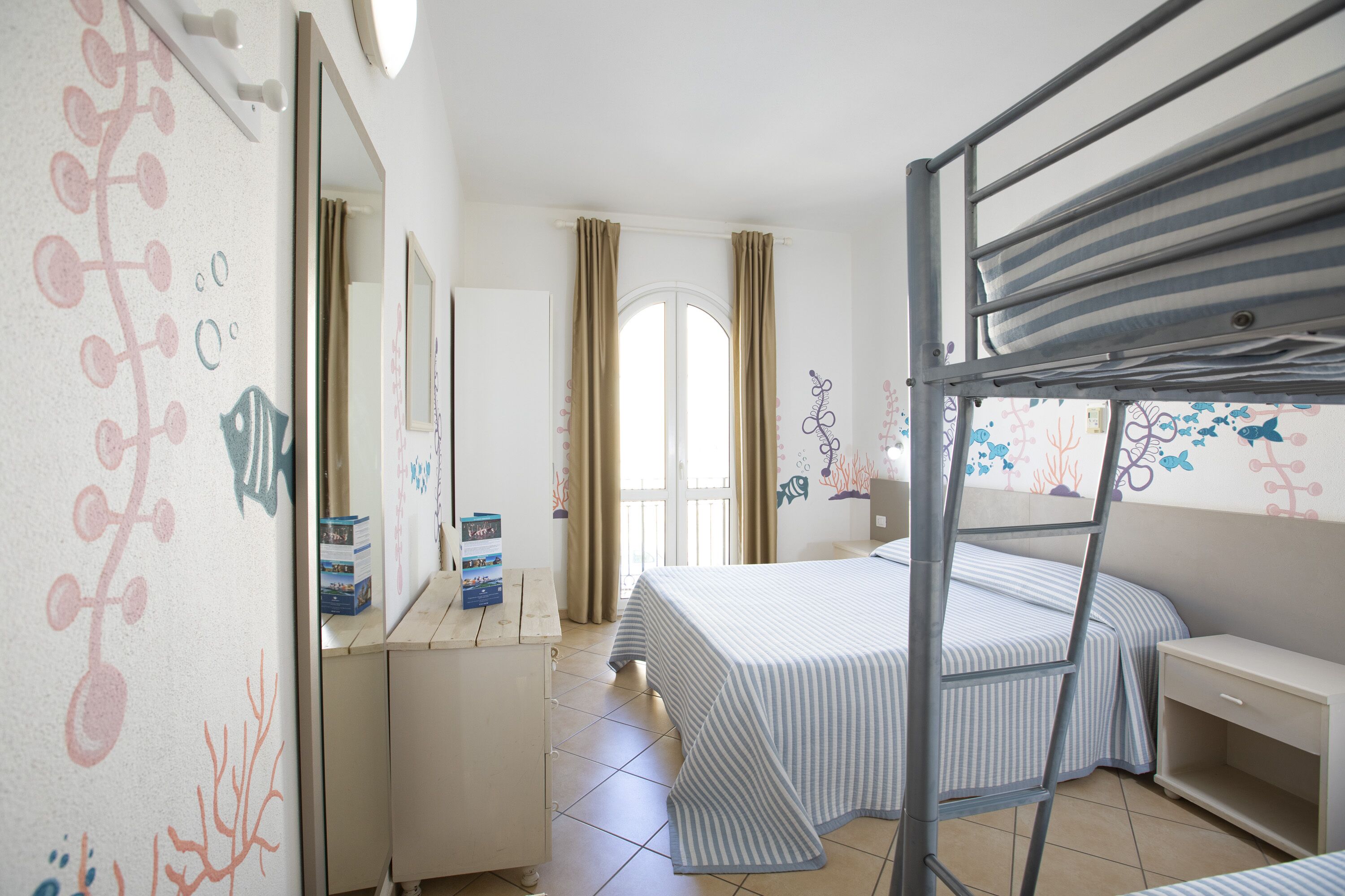 Un dormitorio con literas, un aparador, un espejo y una ventana con cortinas.