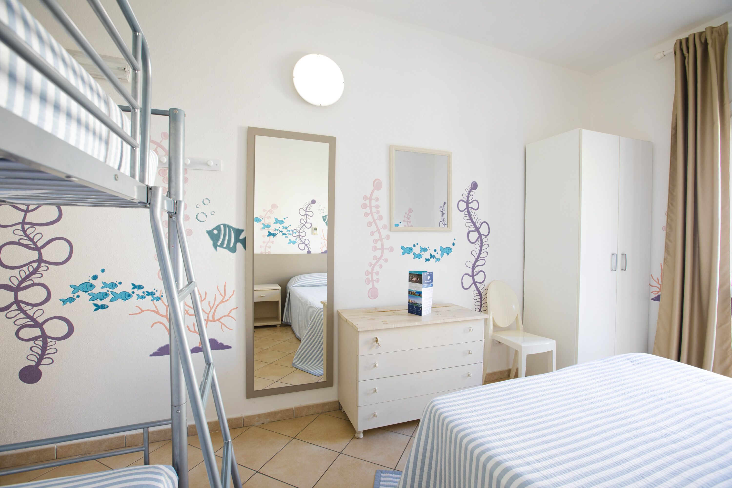 A hotel room with bunk beds, a dresser, a mirror, and a wardrobe.