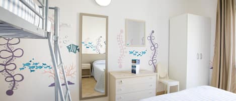 Habitación de hotel con literas, cómoda, espejo y armario.