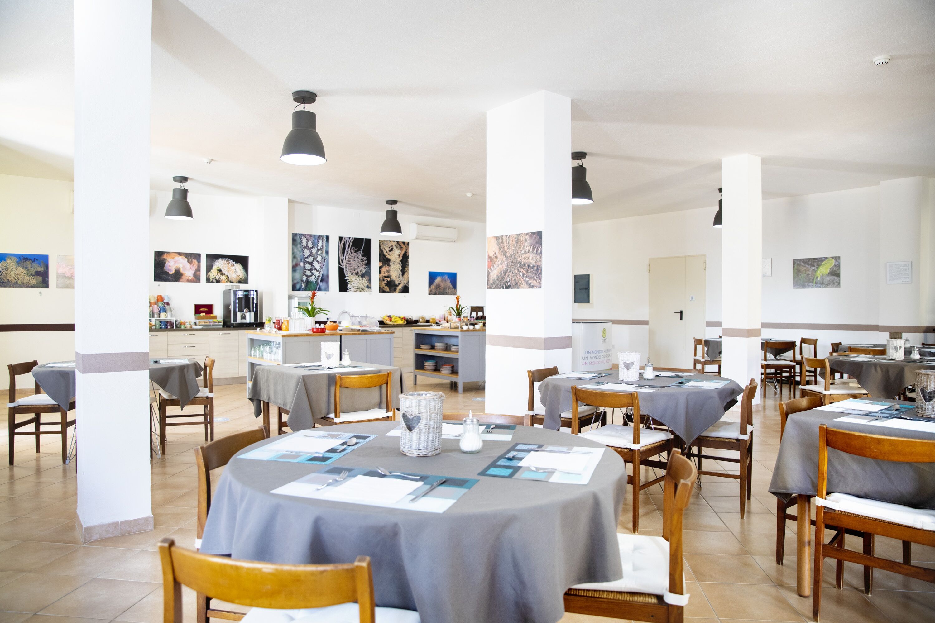 A spacious dining area with round tables, chairs, and pendant lighting.