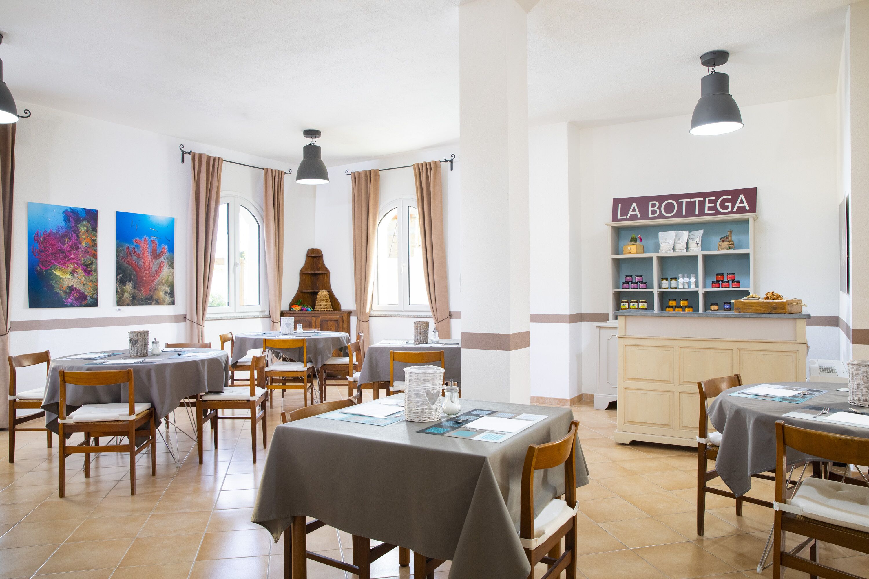 Un comedor con mesas redondas, sillas y un mostrador tipo bufé llamado "LA BOTEGA".