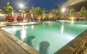 Una piscina con sillones de descanso y una terraza de madera.