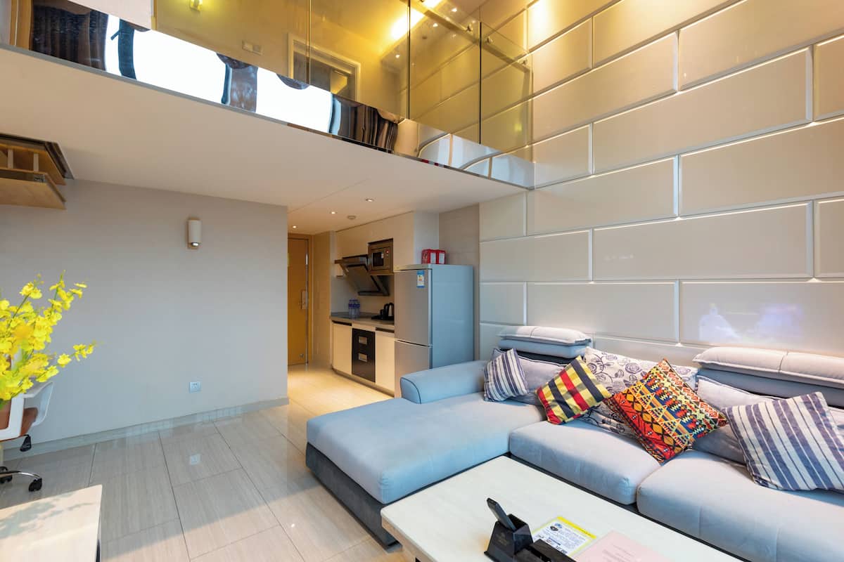 A modern living room with a sectional sofa, a coffee table, and a small kitchen area in the background.