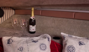 A room with a bed, two pillows, a bottle of champagne, and two glasses. - Boat Sissi Cagliari (Cagliari)