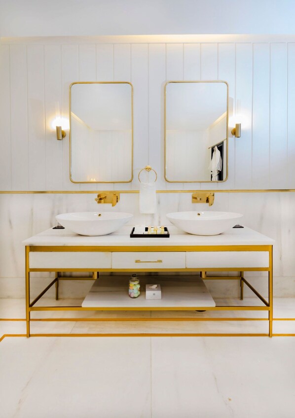 Une salle de bain moderne avec deux vasques, des miroirs à cadre doré et une coiffeuse à cadre doré.