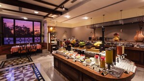 A buffet area with a variety of food items and a seating area with a view of the sunset. - Jehan Numa Palace Hotel (Bhopal)