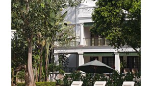 A pool area with lounge chairs and a building in the background. - Jehan Numa Palace Hotel (Bhopal)