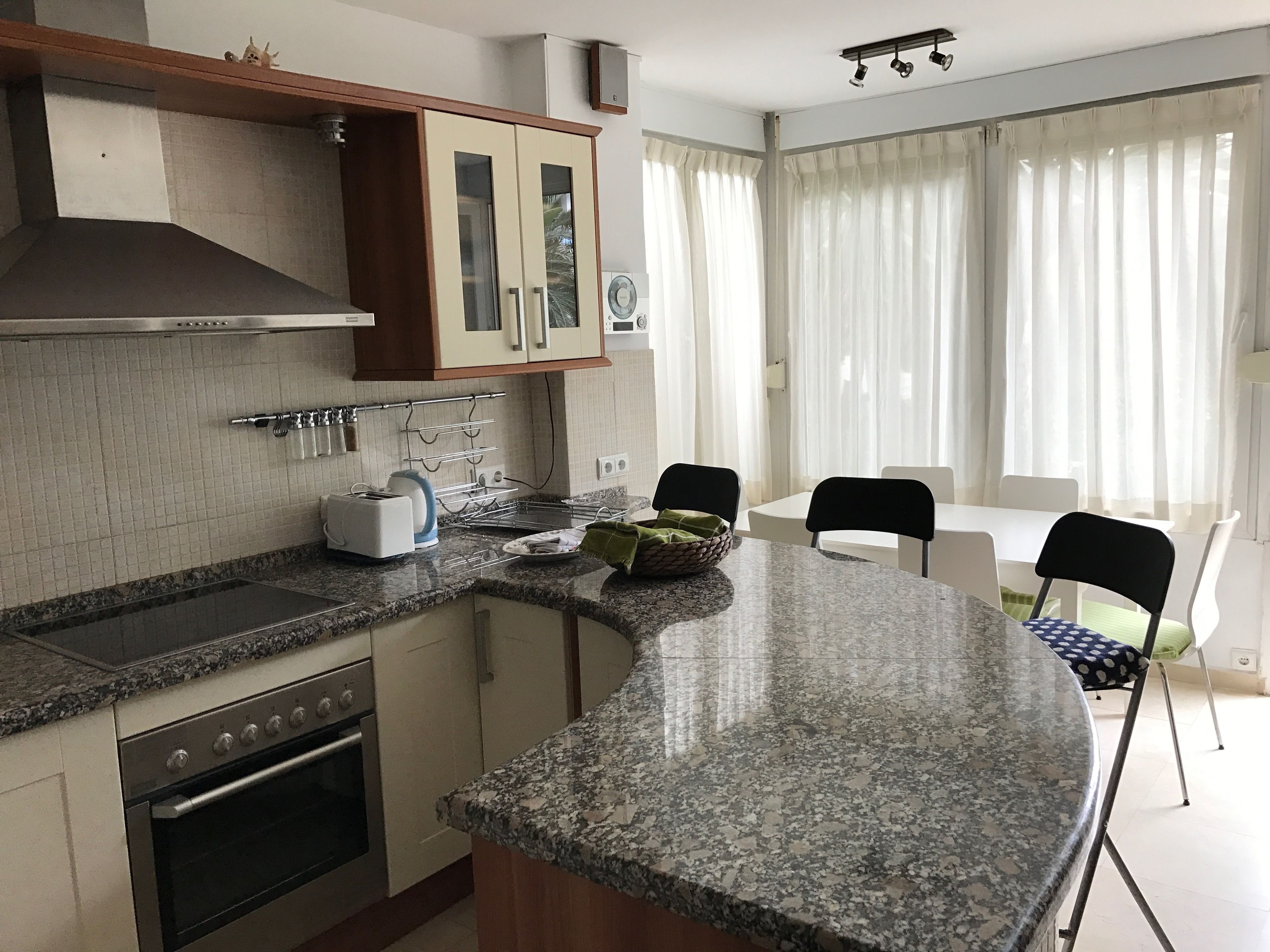 Una cocina con encimeras de granito, horno empotrado y comedor con mesa y sillas.