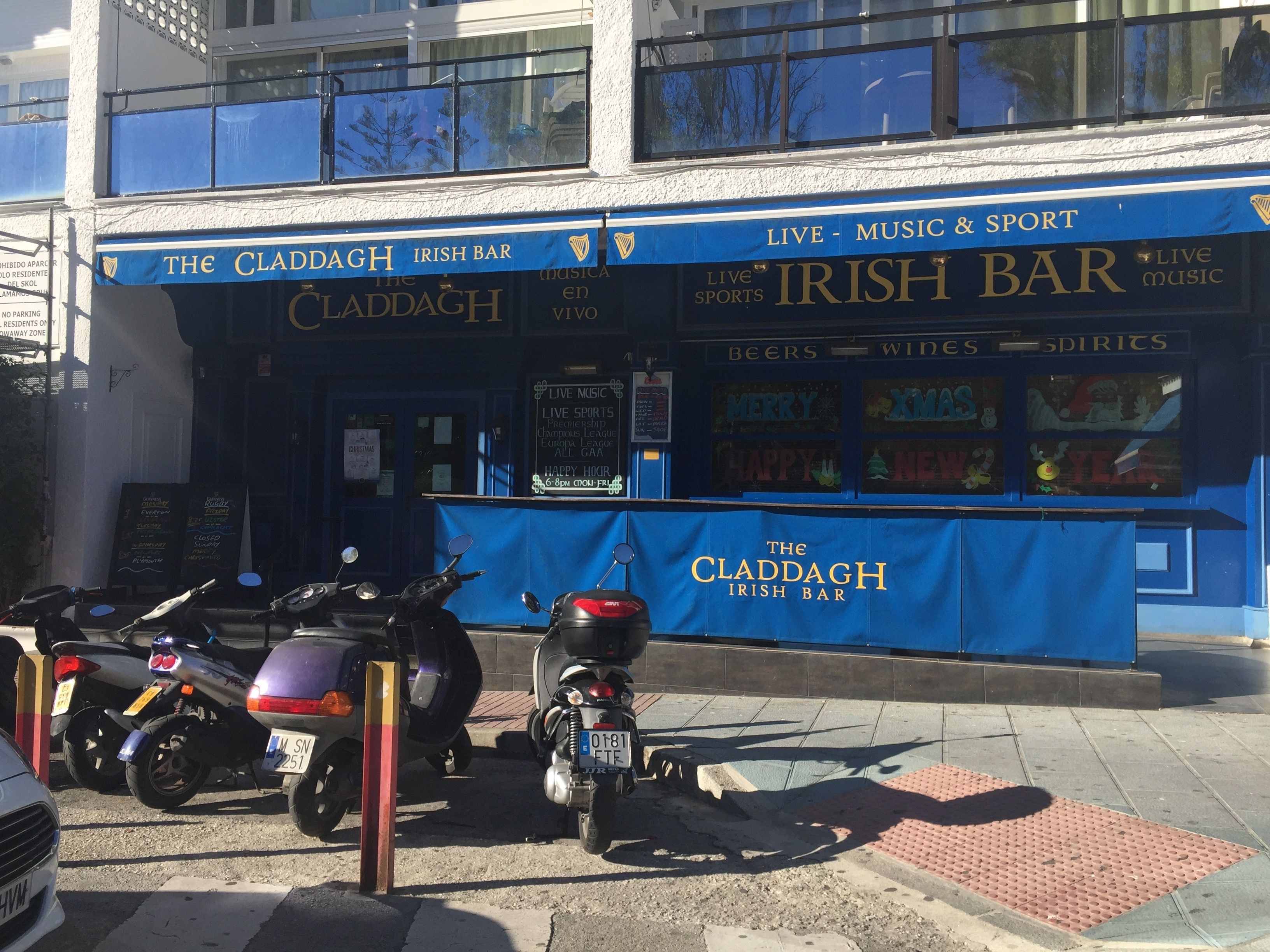 A blue storefront with signage for "The Claddagh Irish Bar" and "Live Music & Sport" services.