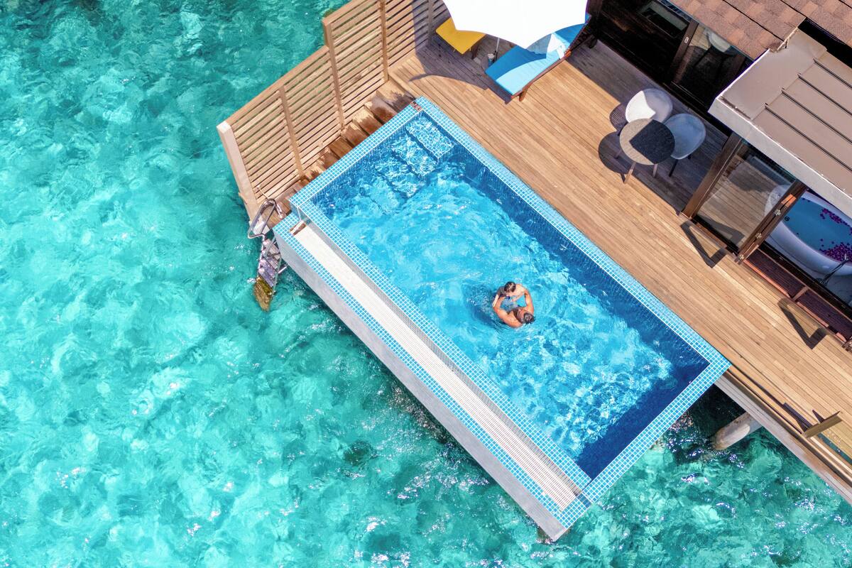 Ein klares, blaues Schwimmbecken mit einer Holzterrasse und Liegestühlen.