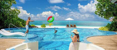 Un espace piscine avec vue sur l’océan, des chaises longues et un jacuzzi.