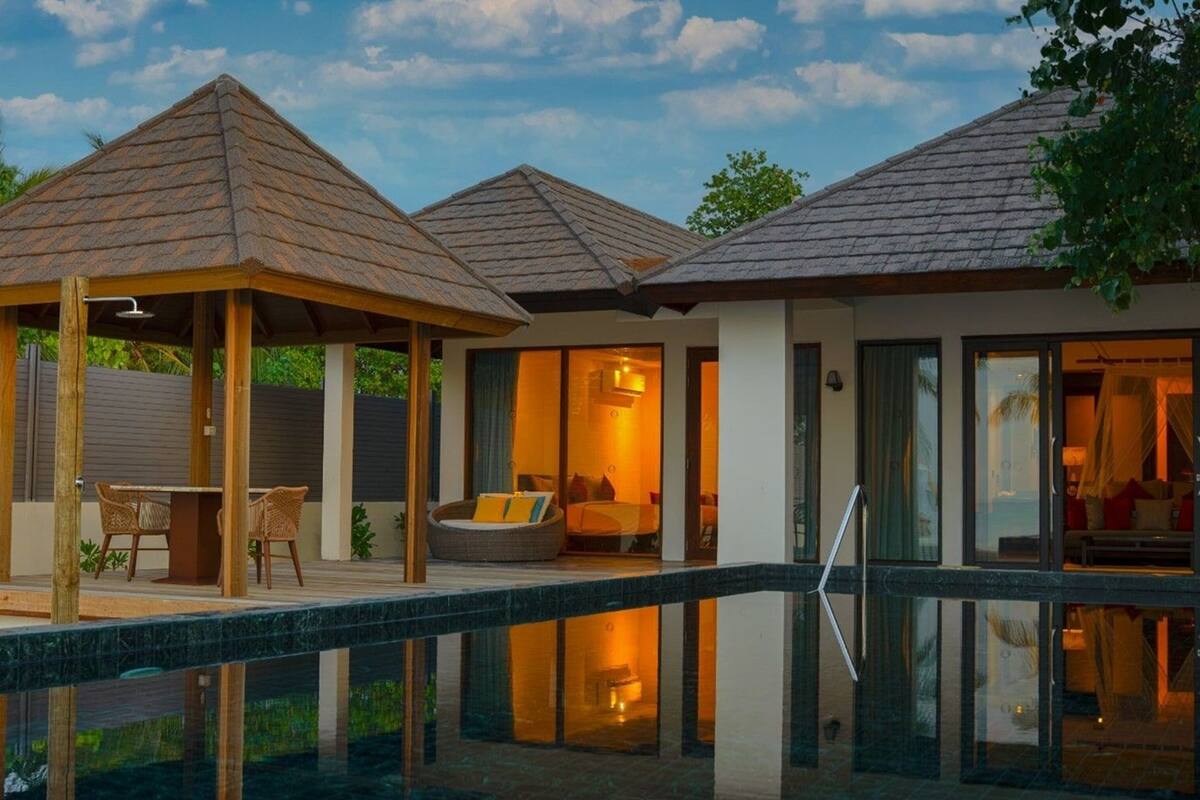 Ein modernes Haus mit Swimmingpool, zwei überdachten Außenbereichen und einem gut beleuchteten Innenraum.