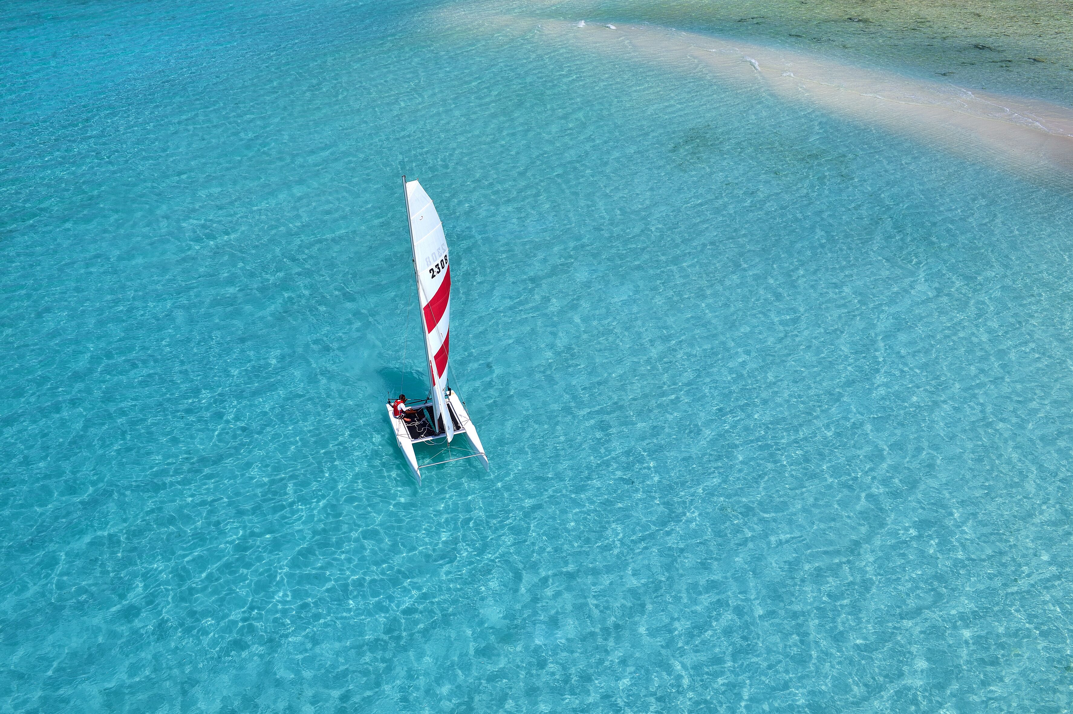 A sailboat on clear turquoise water.