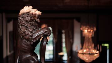 A wooden sculpture of a lion in a room with a chandelier.