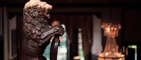 A wooden sculpture of a lion in a room with a chandelier.