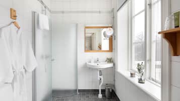 Een moderne badkamer met een douche, wastafel en raam.