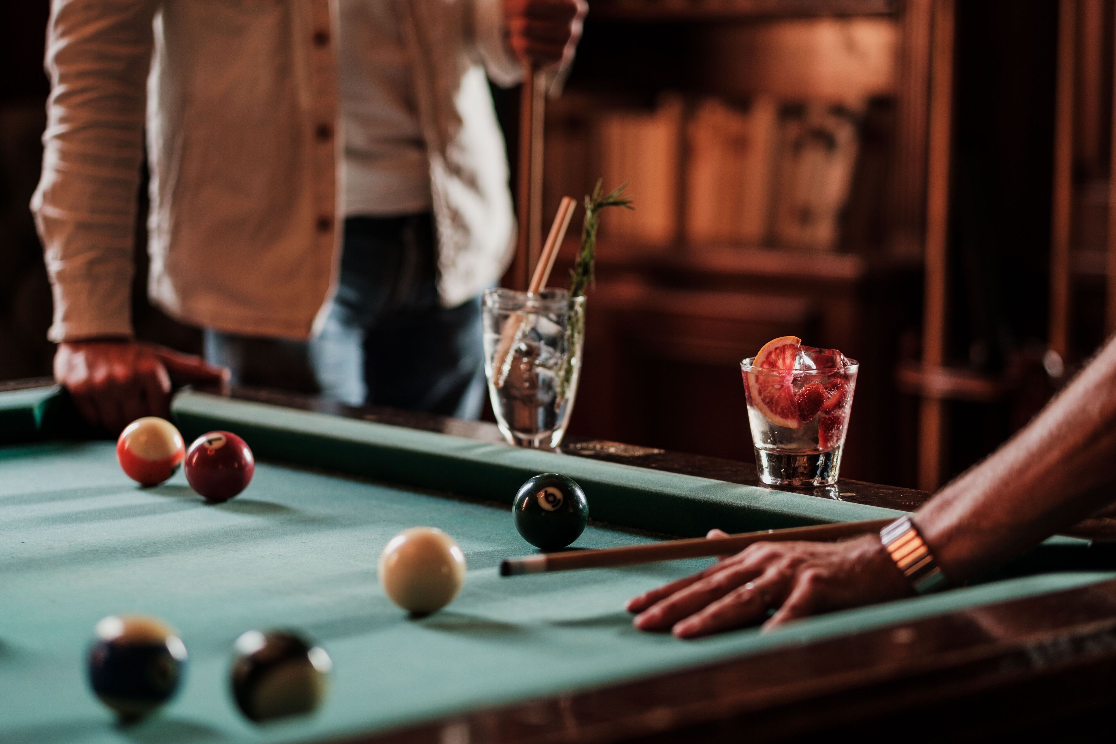 Ein Billardtisch mit Billardkugeln und einem Glas Getränk.