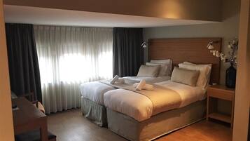 Habitación de hotel luminosa con una cama grande, una mesita de noche y una silla.