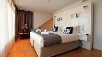A modern bedroom with a large bed, a bedside table, a small table with a vase, and a wall-mounted shelf.
