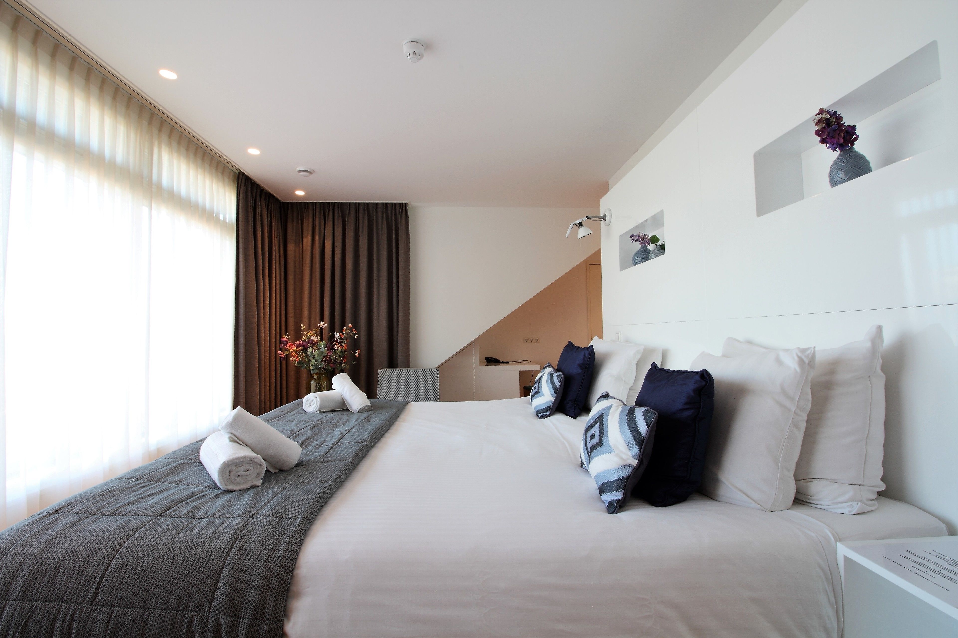 Una habitación de hotel moderna con una cama grande, un escritorio y vistas al exterior.