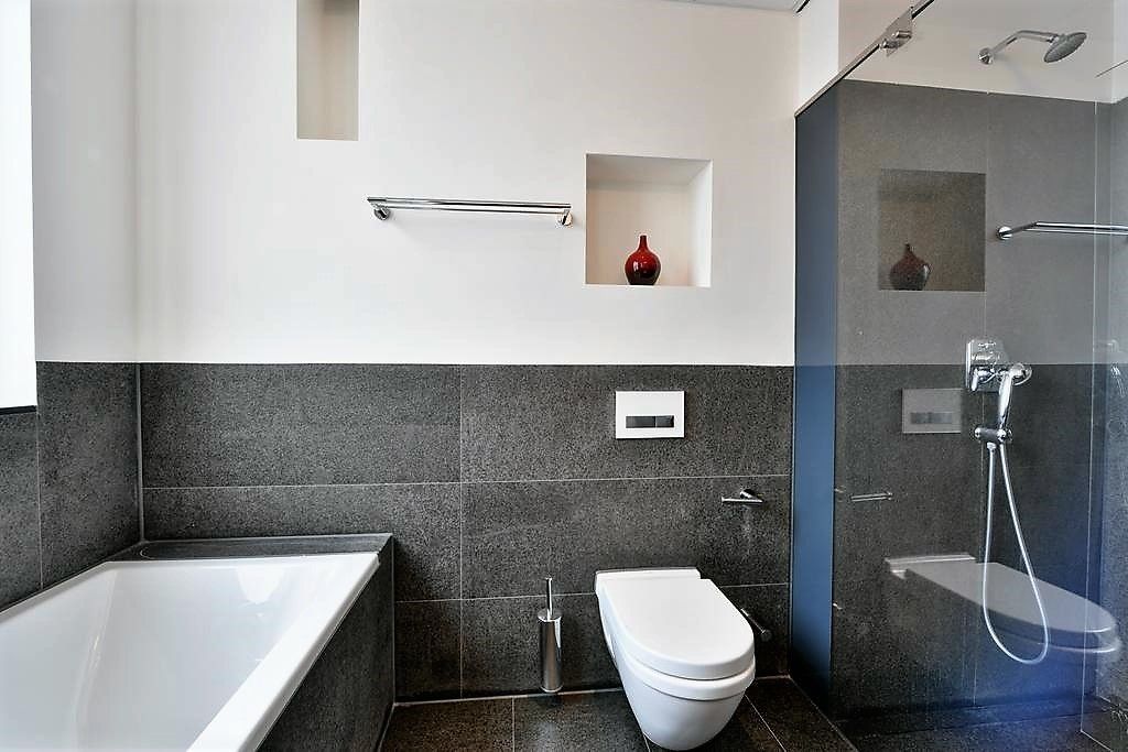 Un baño moderno con bañera, inodoro y zona de ducha.
