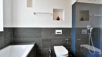 Un baño moderno con bañera, inodoro y zona de ducha.