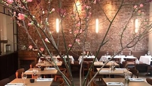 Een restaurant met bakstenen muren, houten tafels en stoelen.