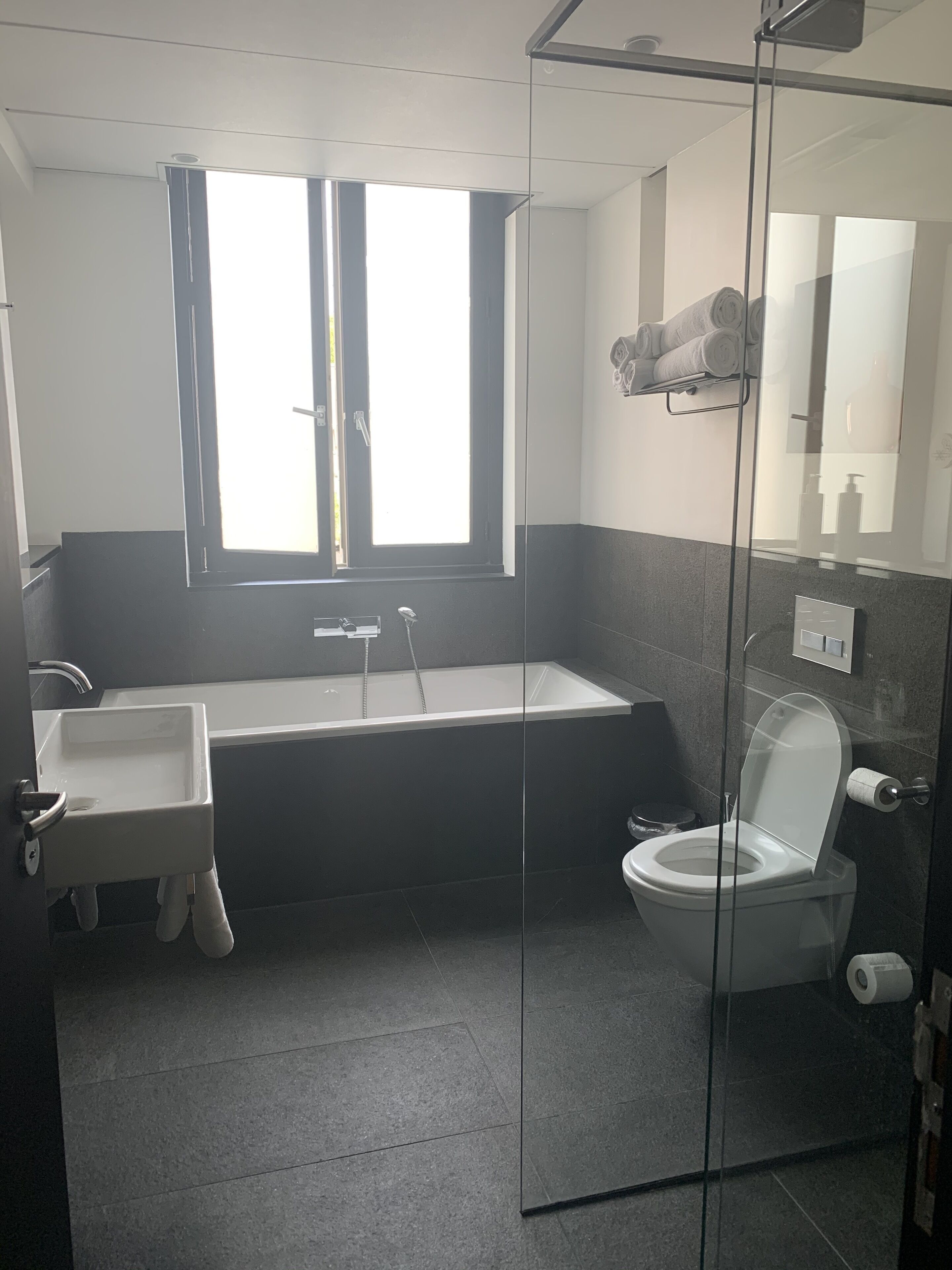 Een moderne badkamer met een bad, toilet en wastafel.