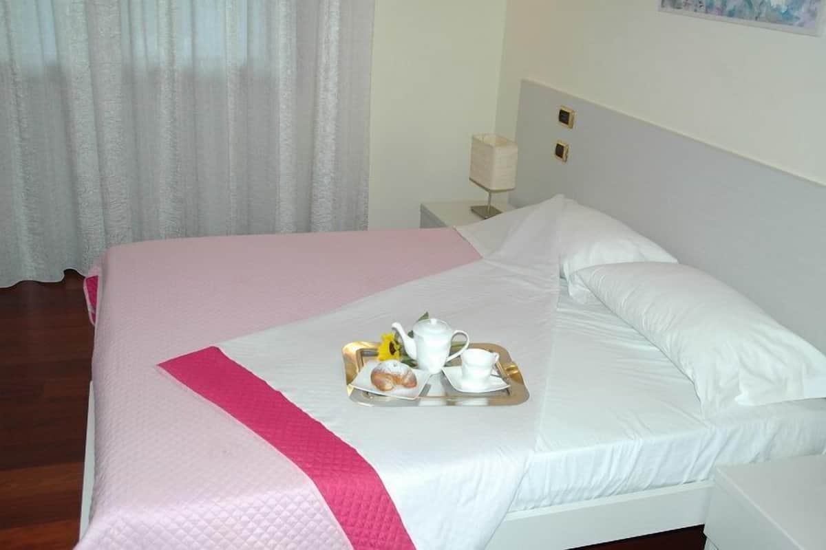 Una cama bien hecha con una bandeja de desayuno, una almohada blanca y una mesita de noche con una lámpara.