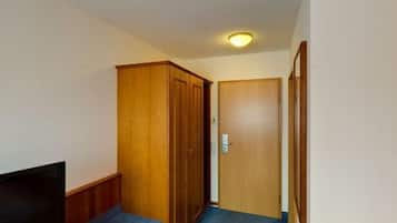 A narrow hallway with a wooden wardrobe, a bench, and a television on a wooden stand.