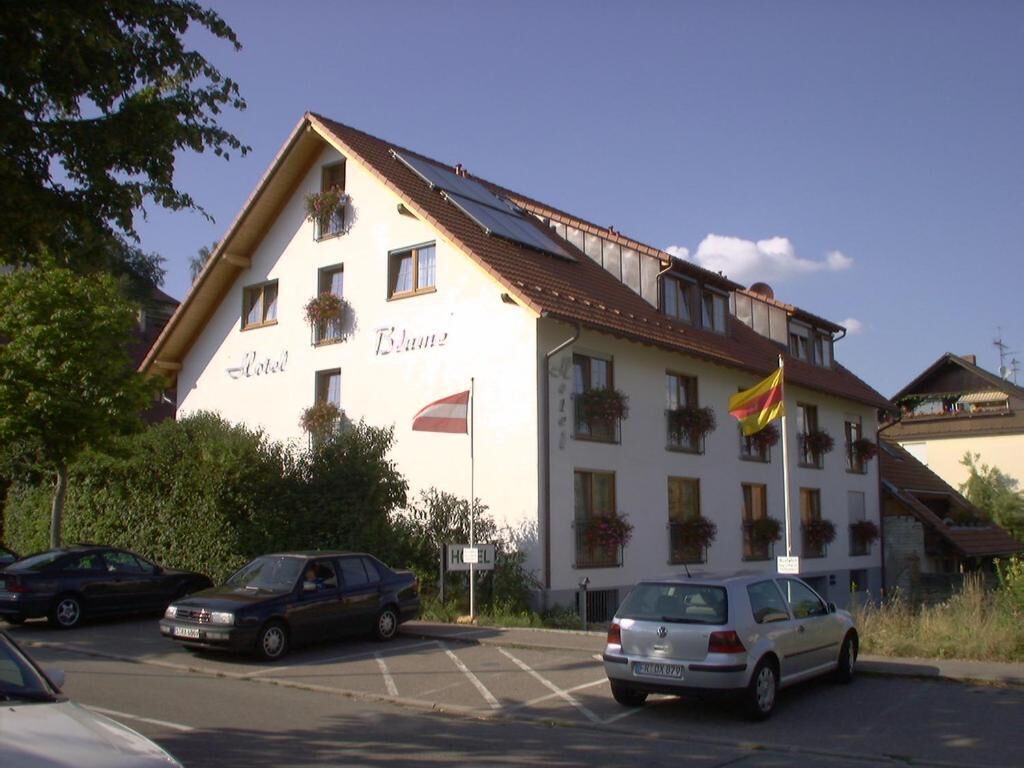 A hotel with a white facade, balconies with flower boxes, and a red flag on the roof.