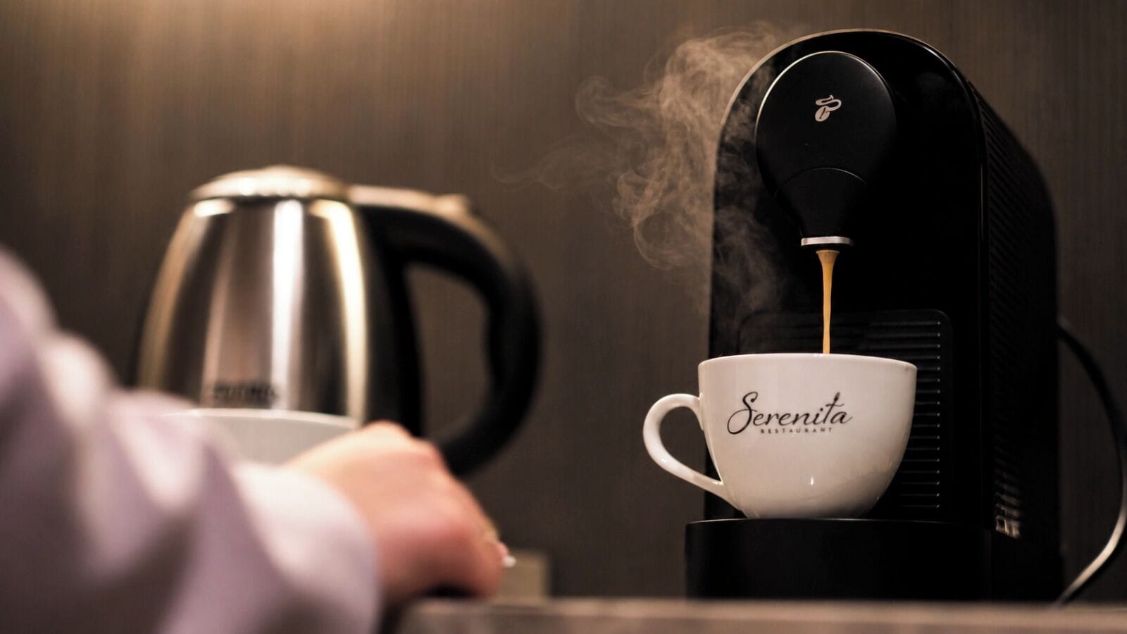 Una máquina de café sirviendo café en una taza con la etiqueta 'Serenita Restaurant'.