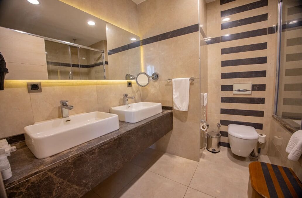 A modern bathroom with two sinks, a shower, and a toilet.