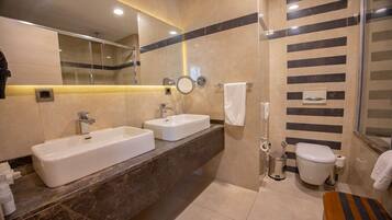 A modern bathroom with two sinks, a shower, and a toilet.
