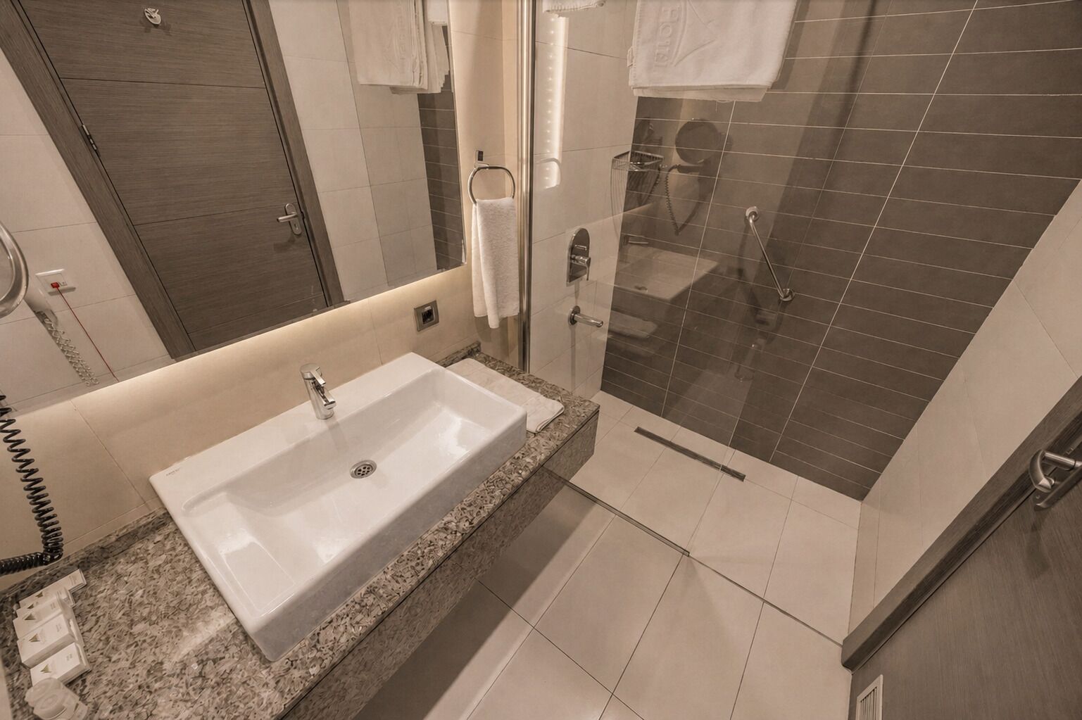 Un baño moderno con un lavamanos grande, cabina de ducha de vidrio y un espejo.