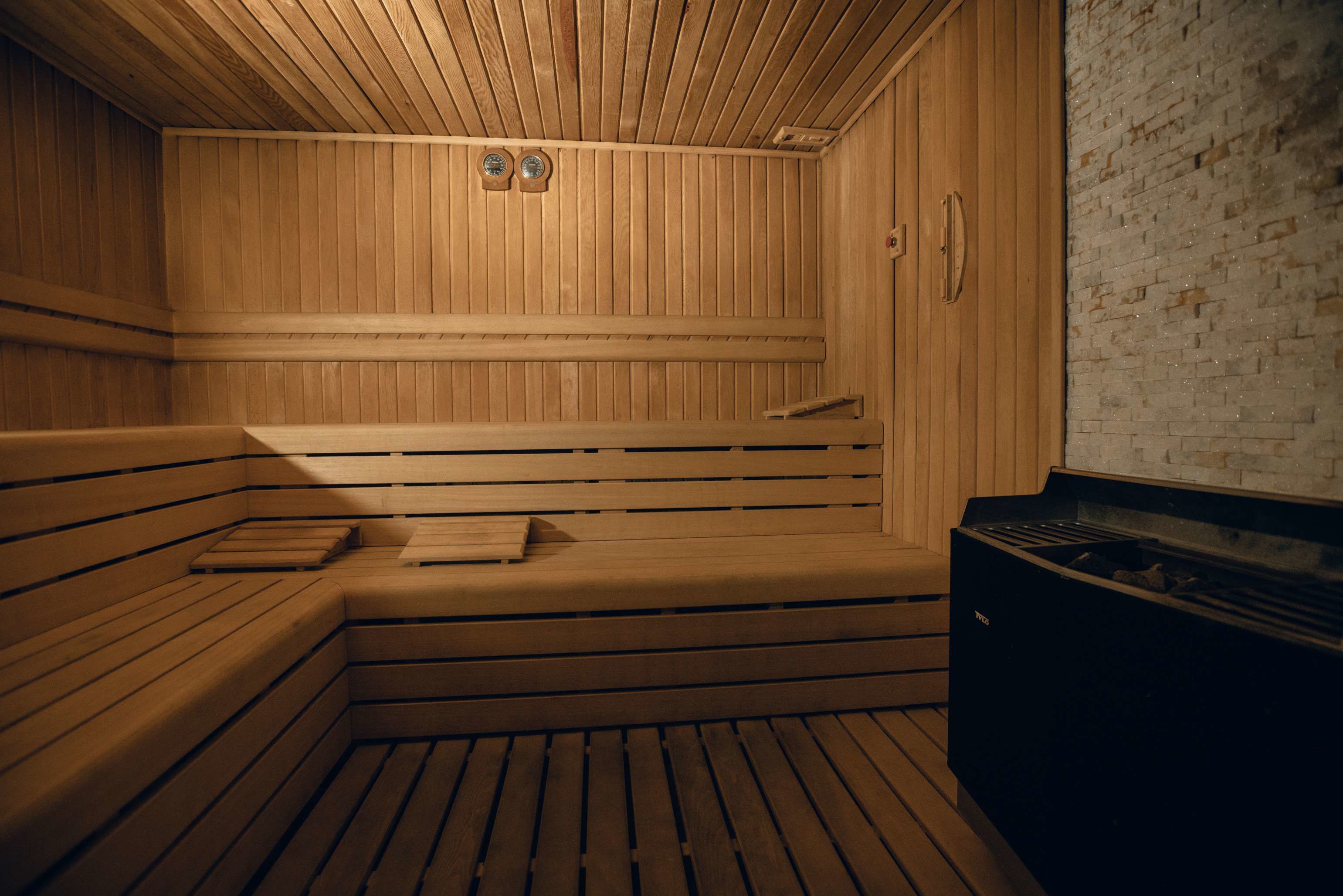 A sauna with wooden benches and a brick wall.