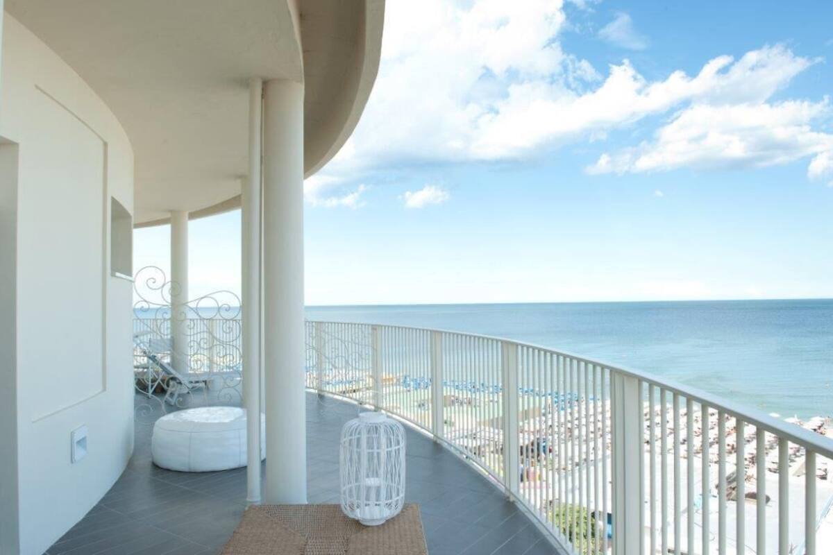 A balcony with a view of the beach and ocean.