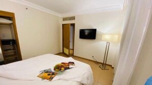 Ein Hotelzimmer mit einem Bett, einem an der Wand montierten Fernseher und einem Nachttisch mit einer Lampe.