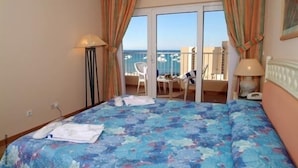 Ein Hotelzimmer mit Bett, Schreibtisch und Meerblick.