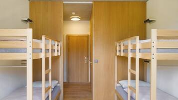 Una habitación con dos literas, paredes de madera, una puerta de madera y una lámpara en el techo.