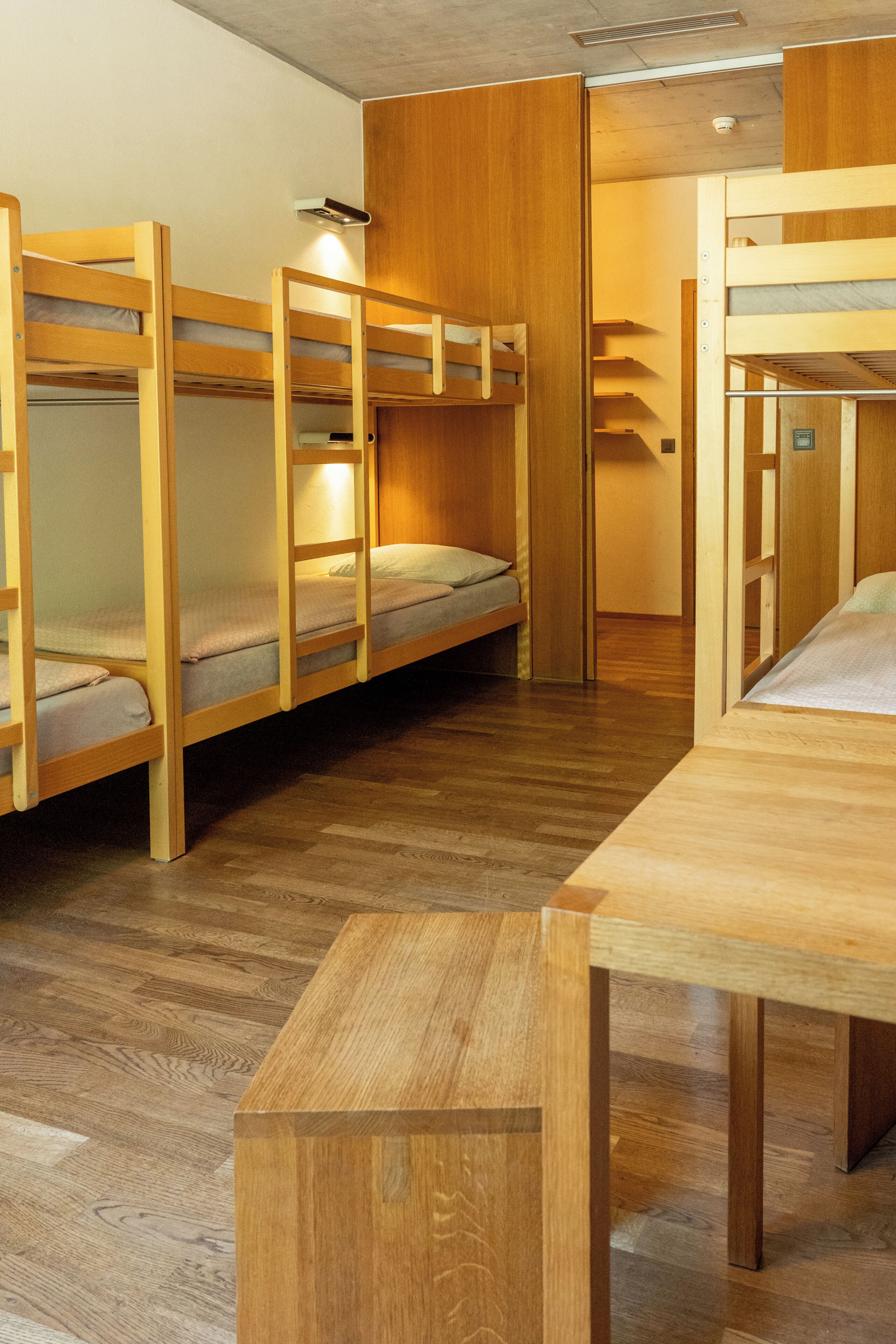 A room with bunk beds, a wooden table, and a light fixture.