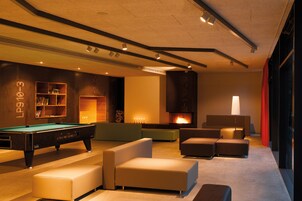 Un área de estar moderna con mesa de billar, sofás y chimenea.