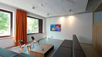 A modern living room with a sofa, chairs, a coffee table, and a TV mounted on the wall.