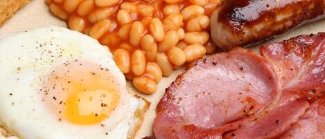 A breakfast plate with eggs, beans, bacon, and sausages.