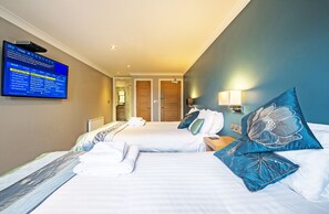 A hotel room with two beds, a TV mounted on the wall displaying channel information, and a door leading to another room. - Dolphin Rooms (Cleethorpes)